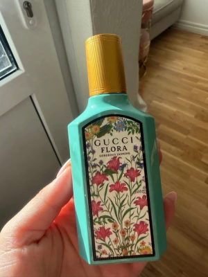 Gucci Flora Gorgeous Jasmine parfym 50ml - Gucci Flora Gorgeous Jasmine Eau de Parfum i en turkosgrön flaska med guldfärgat lock. Flaskan har en färgglad blommig etikett med rosa och gröna detaljer. Lyxig och trendig doft som sticker ut i badrumshyllan. Testad ett fåtal gånger
