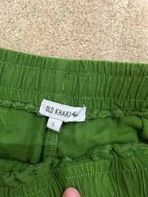 Gröna linnebyxor från Old Khaki - Säljer ett par gröna linnebyxor från Old Khaki i storlek S. Byxorna har resår i midjan med dragsko och raka ben. Perfekta för en avslappnad och chill stil. Materialet är lätt och luftigt, vilket gör dem sköna att bära under varma dagar.