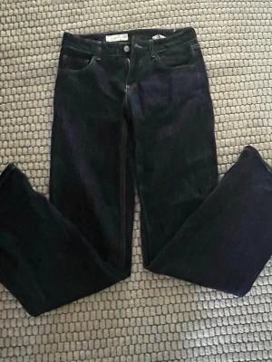 Mörkblå raka jeans - Snygga mörkblå jeans med rak passform och klassisk femficksdesign. Jeansen har silverfärgade knappar och kontrastsömmar. Perfekta till en avslappnad stil och passar till det mesta. Materialet är denim.