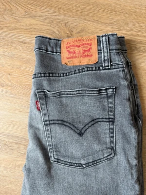 Grå Levi's 501 raka jeans - Säljer ett par grå Levi's 501 jeans med rak passform och klassisk femficksdesign. Jeansen har en snygg tvättad look, normal midja och är tillverkade i slitstark denim. Perfekta för dig som gillar en tidlös och avslappnad stil.