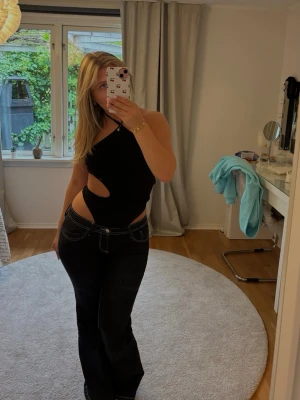 Svart body  - Trendig svart halterneck body med  cut-outs i sidorna. Bodyn är tight och har en unik asymmetrisk design.