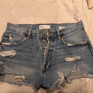 Jeansshorts - Säljer ett par blå denimshorts från Zara i storlek 36. Shortsen har låg midja, slitna detaljer!💕💕 Perfekta för sommaren!! Skriv gärna för frågor och svar💕💕