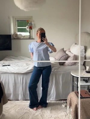 Ljusblå blus med puffärm - Snygg ljusblå blus med puffiga korta ärmar och rund halsringning. Blusen har en avslappnad passform och är tillverkad i ett tunt, vävt material som känns luftigt. Perfekt att styla med jeans eller kjol för en trendig look.