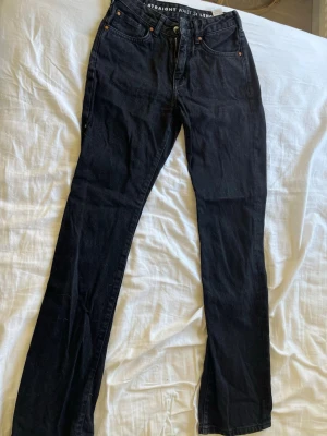Svarta straight jeans  - Säljer ett par svarta jeans (tror de är från BikBok ,ej säker) med low waist och straight fit. Klassisk femficksmodell med knappgylf och nitar. Jeansen är i ett mjukt denimtyg och har en tidlös look som passar till det mesta.