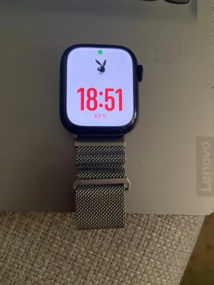 Apple Watch med metallarmband - Snygg Apple Watch med svart urtavla och ett stilrent silverfärgat mesh-armband i metall. Klockan har en modern design och digital display. Perfekt för dig som vill ha koll på tiden och notiser direkt på handleden. Laddar medföljer men utan kartong och kvitto