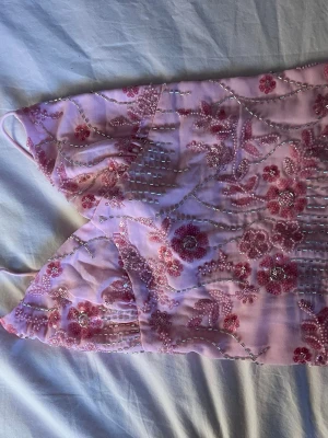 Dekorerad backless sommar topp med glitter  - Glittrig top perfekt inför sommaren dekorerad med paljetter och pärlor. Oanvänd och i bra skick. Knyts där bak och passar perfekt på stranden 
