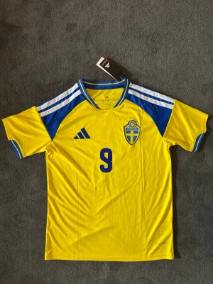 Sverige VM 26/27 hemma Isak 9 - Fotbollströja med Isak på ryggen. Tröjan är helt ny med tagg kvar och i perfekt skick. Perfekt för dig som är supporter, samlar på fotbollströjor eller vill ha en snygg tröja till träning och vardag.                                                                      🟡 Skickas inom 24 timmar.                                         Vid intresse eller frågor är det bara att skicka 👍