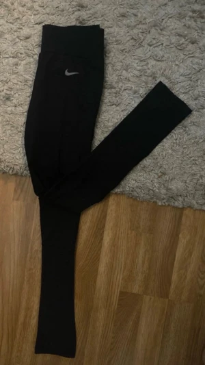 Svarta Nike träningsleggings - Säljer ett par svarta Nike träningsleggings med reflekterande logga. Tight passform och stretchigt material som passar perfekt till träning eller chill. Diskreta detaljer och klassisk Nike-design. Strl M, passar även S. 