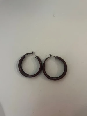 Mörkröda hoops örhängen - mörkröda hoops örhängen i plast med metallstift, aldrig kommit till användning. Köpte på marknad utomlands  