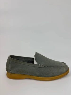 Loro Piana summer walk loafers - Stilrena loafers i grå mocka med klassisk design och kontrasterande ljusbrun gummisula. Skorna har diskreta sömmar och en enkel slip-on-modell som ger en clean look. Perfekta för dig som gillar en avslappnad men ändå snygg stil.
