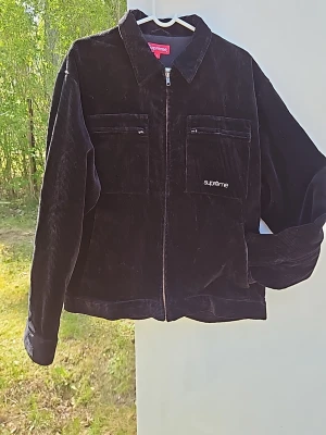 Svart manchesterjacka från Supreme - Supreme svart manchesterjacka med dragkedja framtill och två stora bröstfickor med zip. Diskret Supreme-logga broderad på ena fickan. Klassisk rak passform och mjukt manchestertyg som ger en cool vintagekänsla.