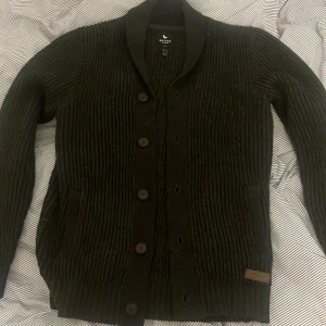 Mörkgrön ribbstickad cardigan - Denna eleganta kofta har en ribbad design med knappar framtill och två fickor och även innerfickor. 
