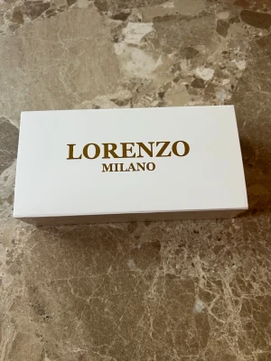 Guldfärgad klocka Lorenzo Milano - Stilren guldfärgad klocka från Lorenzo Milano med fyrkantig urtavla och romerska siffror.