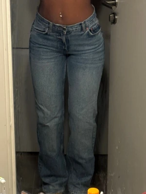 Blå raka jeans med låg midja  - Snygga blå jeans med rak passform och låg midja Klassisk femficksmodell med knapp och dragkedja framtill. Jeansen har en tidlös tvätt och är tillverkade i denim. Perfekta för en avslappnad och trendig look.