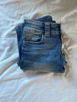 Blå bootcut jeans med slitningar - Säljer dess low waist jeans från HM i storlek 146❤️Sitter perfekt på benen och kan även bäras som en 152!❤️❤️