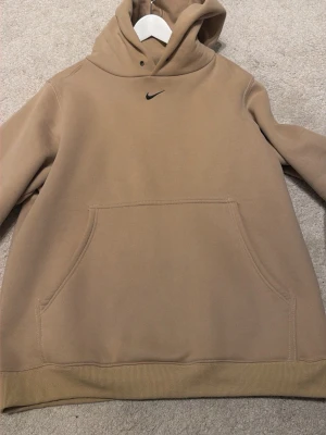Vintage hoodie från Nike  (passar L) - Snygg beige hoodie från Nike med klassisk känguruficka och liten svart swoosh-logga på bröstet. Tillverkad i 100% bomull för en mjuk och skön känsla. Perfekt för en chill och avslappnad stil. PASSAR STORLEK L