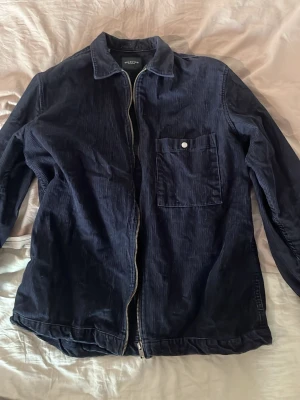 Mörkblå manchester overshirt - Snygg mörkblå overshirt från Selected Homme i mjuk manchester. Jackan har dragkedja framtill, klassisk krage och en bröstficka med knapp. Perfekt lager på lager-plagg med avslappnad passform och stilren look.