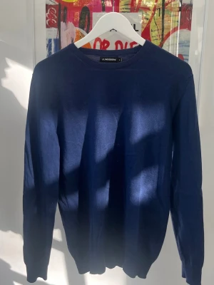 Mörkblå tröja från J.Lindeberg - Snygg mörkblå tröja från J.Lindeberg i klassisk modell med rund halsringning och långa ärmar. Tillverkad i ett mjukt och tunt material som passar perfekt till lager på lager. Enkel och stilren design utan mönster eller tryck.