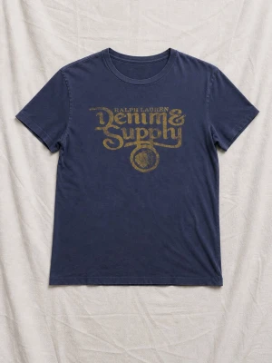  Ralph Lauren Denim & Supply T-shirt - Snygg blå t-shirt från Ralph Lauren Denim & Supply med gul vintageinspirerad logga på bröstet. Tillverkad i 100% bomull och har en klassisk passform med korta ärmar och rund hals. Perfekt för en avslappnad och cool stil.