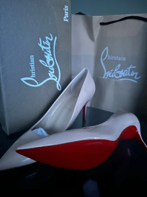 Beige lackpumps från Louboutin - Säljer ett par klassiska pumps från Christian Louboutin i beige lack med spetsig tå och ikonisk röd sula. Skorna har smal klack och elegant siluett, perfekta för att lyfta vilken outfit som helst.