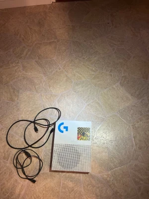 Xbox One S vit spelkonsol - Säljer en Xbox One S i snygg vit färg med svart detalj. Konsolen har en stilren, rektangulär design och är tillverkad i plast. HDMI-kabel och strömkabel ingår. Perfekt för gaming och streaming.