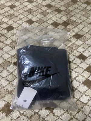 Svarta mjukisbyxor från Nike - Svarta mjukisbyxor från Nike med klassisk vit swoosh-logga på vänster lår. Byxorna har dragsko i midjan och raka ben. Perfekta för chill eller träning. Tillverkade i mjukt material för maximal komfort.