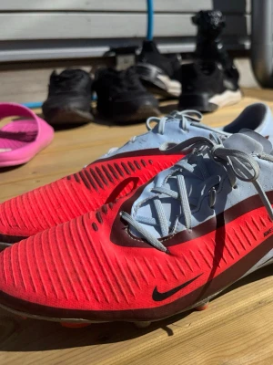 Nike fotbollsskor Phantom  Academy FG AG - Helt nya KÖPTE DE FÖR 2 veckor sedan därför kostar de lite mer Säljer ett par Nike fotbollsskor i snygg röd och ljusgrå färg med svarta detaljer och snörning. Om du har några frågor så kan du komma privat 🤗🤗🤗