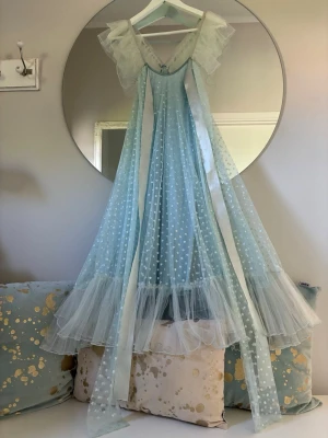 Oanvänd Ida Sjöstedt-dröm i isblå färg med tyll & glitter – Perfekt för fest & bröllop - Säljer en magiskt vacker klänning från svenska designern Ida Sjöstedt. Klänningen är i en ljuvlig isblå nyans och har märkets signifikanta eteriska stil med lager av mjukt tyll och fina detaljer.     Klänningen har en smickrande passform med eleganta axelband och dekorativa volangdetaljer vid axlarna. Tyget är prytt med ett diskret glittrande prickmönnster som ger ett lyxigt och drömskt intryck. Fin volangkant nertill som skapar vacker volym och rörelse.Klänningen är i perfekt skick. 