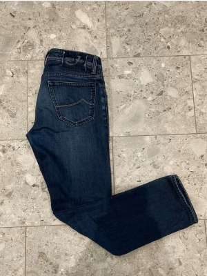 Mörkblå jeans från Jacob Cohen - Snygga mörkblå jeans från Jacob Cohen med klassisk femficksmodell och raka ben. Jeansen har kontrastsömmar och en diskret logga på bakfickan. Tillverkade i mjukt denimtyg som ger en skön passform och stilren look.