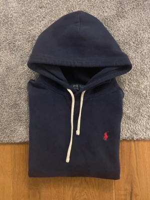 Ralph Laurent hoodie mörk blå  - Ralph Lauren hoodie i mörkblå färg säljes. En klassisk och stilren hoodie som passar till allt med inga deflekter eller skador. Snabb leverans efter köp! 📦 Har du några frågor eller vill se fler bilder är det bara att höra av dig, så svarar jag så snabbt jag kan. 😊
