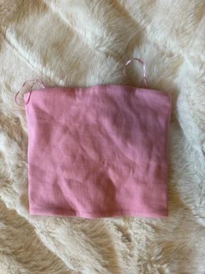 Ljusrosa bandeautopp croppad - Säljer en ljusrosa bandeau tubtopp. Toppen är ribbad och har en enkel, stilren design. Materialet känns mjukt och stretchigt. Aldrig använd från Zara! 