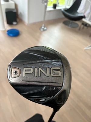 PING G400 golfklubba driver. - Säljer en svart PING G400 driver, perfekt för golfare som vill ha extra kraft i slagen. Nytt golf Pride grepp och regular skaft. Klubban har en modern design med tydlig logga och detaljer i silver. Tillverkad i metall och kompositmaterial för bästa prestanda. En av de mest legendariska klubborna inom golf världen. Söker även byte