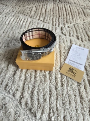 Burberry bälte  - Bältet är tvåsidigt och kommer i färgen beige och färgen svart alltså att man kan ändra så att man antingen har en svart färg eller den klassiska burberry färgen 