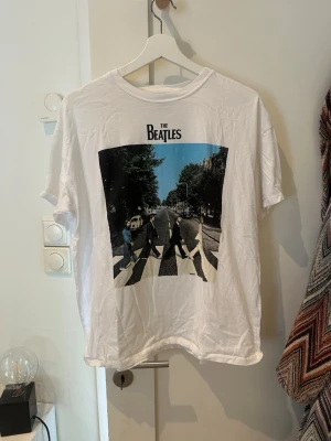 The Beatles Abbey Road t-shirt vit - Säljer en vit t-shirt med ikoniskt Abbey Road-tryck från The Beatles.