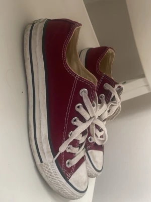 Röda Converse All Star låga sneakers - Klassiska röda Converse All Star sneakers med vit gummisula och vita snören. Skorna har lågt skaft, canvasmaterial och svarta detaljer på sulan. Perfekta för en avslappnad och cool stil. Dom är sparsamt använda o är fortfarande i mycket gott skick. 