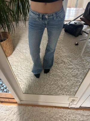 Ljusblå bootcut jeans med detaljer - Säljer ett par ljusblå bootcut jeans med snygga broderade fickor bak och coola sömdetaljer. Jeansen har klassisk femficksdesign och är tillverkade i denim med lite stretch för skön passform. Perfekt för dig som gillar en avslappnad och trendig look. Storlek 152🩷