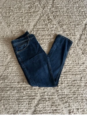 Mörkblå donup jeans George  - Säljer ett par mörkblå skinny donup jeans med klassisk femficksdesign och normal midja. Jeansen har smal passform och är tillverkade i stretchigt denimtyg för extra komfort. Perfekta för dig som gillar en enkel och stilren look.