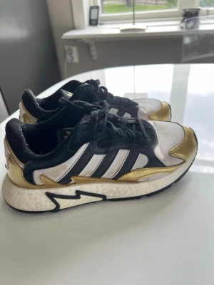 Adidas sneakers med guld och svart - Snygga Adidas sneakers med vit mesh, svarta detaljer och metallic guld på tå och häl. 