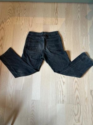 Svarta raka jeans från Jack & Jones - Säljer ett par svarta jeans från Jack & Jones med rak passform och klassisk femficksdesign. Jeansen har en något tvättad look och är tillverkade i denim. Perfekta för dig som gillar en avslappnad och stilren stil.