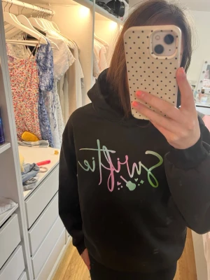 Svart Swiftie hoodie - Snygg hoodie med skönt material i med texten Swiftie på 💖 (INTE riktig Taylor Swift merch) men jättefin oavsett om riktig merch. Dock vet jag inte märket eller storleken men själv skulle jag säga storlek XXS-XS🤍 fint skick har aldrig används