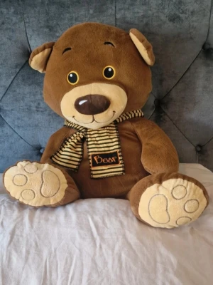 Stor brun nallebjörn med scarf - Ca 68 cm hög från fot till huvud. Det är lite nopprigt på halsduken och några trådar har letat sig upp från sömmar, inget som jag tror spelar någon roll förutom vänster öra som kan behöva säkras (se bilder).