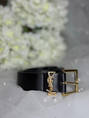 Svart bälte från Yves Saint Laurent - Snyggt svart bälte från Yves Saint Laurent med klassiskt YSL-spänne i guld. Bältet är gjort i slätt skinn och har en stilren, elegant design som passar till många olika outfits. Perfekt accessoar för att lyfta din look.