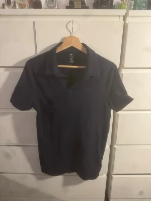 Mörkblå slim fit piké från H&M - Snygg mörkblå pikétröja från H&M i slim fit-modell. Klassisk krage och kortärmad design, perfekt för en clean och enkel stil. Tillverkad i mjuk bomull som känns skön mot huden.