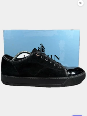 Lanvin - Snygga svarta sneakers från lanvin med mocka på sidorna och blankt läder på tån. Skorna har svarta skosnören och en låg profil som passar perfekt till jeans eller chinos. Klassisk design med diskreta detaljer och robust gummisula.