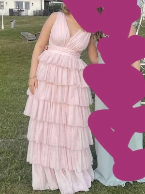 Ljusrosa balklänning  - Supersöt balklänning i ljusrosa med flera lager volanger som är v-ringning. Klänningen är i helt nytt skick då jag bara har haft på mig den en gång. Orginal priset var 1800kr, Perfekt för speciella tillfällen.