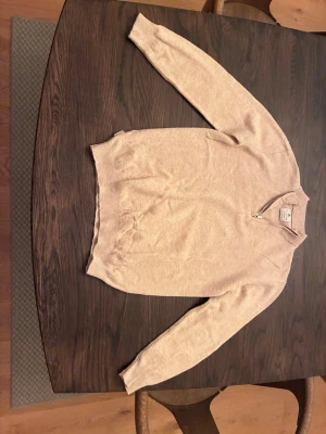 Beige stickad tröja Scalpers - Stickad tröja i mjuk beige ton från Scalpers Kids Collection. Tröjan har halv dragkedja vid halsen, ribbstickade muddar och klassisk passform. Perfekt för dig som gillar stilrena och enkla plagg med en modern touch. 152 cm