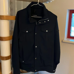 J.Lindeberg fieldjacka  - Säljer en mörkblå fieldjacka från J.lindeberg i modell Bailey i storlek S. Den är i nyskick. Nypris är 3500