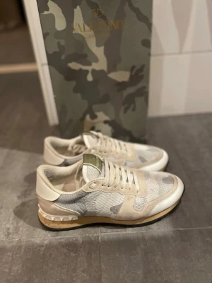 Valentino rockrunners  - Snygga sneakers från Valentino i beige och vit camo-design. Skorna har detaljer i mocka och mesh, samt en unik nitar-detalj på hälen. Gummisula med bra grepp och klassisk låg profil. Perfekta för dig som gillar exklusiva och trendiga sneakers.