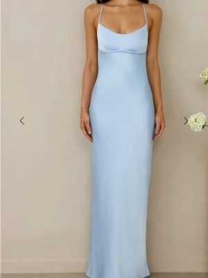 Ljusblå bal klänning  - Elegant ljusblå långklänning med smala axelband och öppen rygg med snörningsdetalj. Klänningen har en figurnära passform och är tillverkad i ett glansigt satinliknande material som ger en lyxig känsla. Har endast testat den en gång men eftersom den ej passa så säljer jag den, ny pris var 1400 kr 💕 