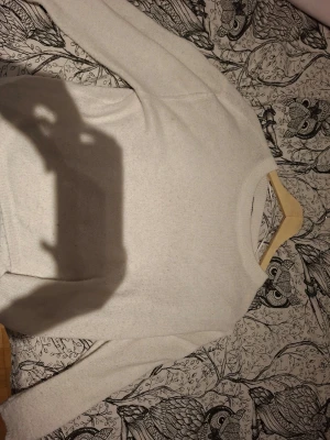 Vit stickad tröja med rund hals - Klassisk vit stickad tröja med rund hals och långa ärmar. Tröjan har en enkel och stilren design som passar till det mesta. Perfekt för lager på lager och enkel att matcha med olika outfits.